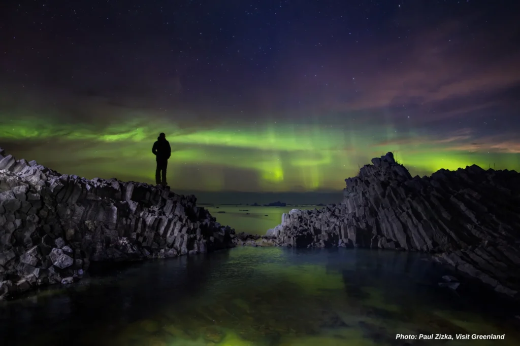 Hiker & volcanic rooks on Disko Island. Photo - Paul Zizka , Visit Greenland