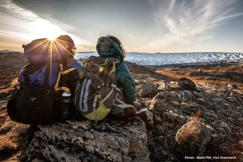 Two hikers enjoying the sunset over the edge of the Greenland Ice Sheet near Kangerlussuaq