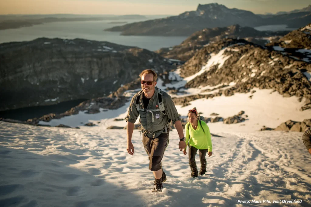 Two hikers on a slope of summer snow ascending Ukkusissaq - Store Malene outside Nuuk in Greenland
